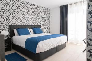 a bedroom with a bed with blue and white sheets at Hostal Boutique I Host You in Madrid