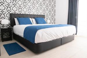 1 dormitorio con 1 cama grande con sábanas azules y blancas en Hostal Boutique I Host You, en Madrid