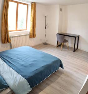 a bedroom with a blue bed and a desk at La Biquette in Novy-Chevrières