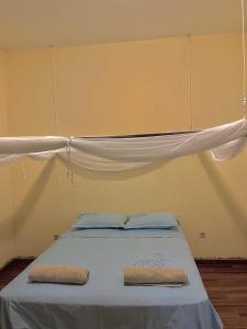 a bed with a white canopy and two pillows on it at CC House in Chidenguele