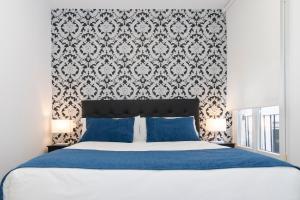 1 dormitorio con cama con almohadas azules y papel pintado en Hostal Boutique I Host You, en Madrid
