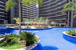 a pool with palm trees and a large building at Landscape Beira Mar Fortaleza in Fortaleza