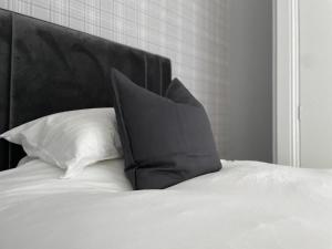 a black pillow sitting on a bed with white pillows at The Lugton Rooms 