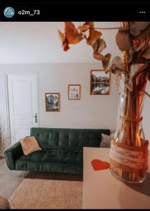 a green couch in a living room with a vase at O2M Gresy sur aix in Mognard