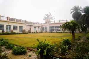 un edificio con una palma di fronte a un cortile di Shree Krishna Bhakti Ashram a Vrindāvan