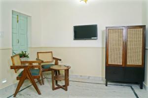 Shree Krishna Bhakti Ashram في فريندافان: غرفة معيشة مع كراسي وطاولة وتلفزيون