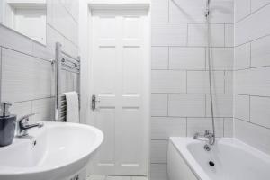 a white bathroom with a sink and a bath tub at Stunning Top 2 Bed Flat Tilbury Central Location in Tilbury