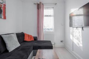 a living room with a black couch and a table at Stunning Top 2 Bed Flat Tilbury Central Location in Tilbury