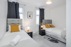 a bedroom with two beds and two windows at Stunning Top 2 Bed Flat Tilbury Central Location in Tilbury