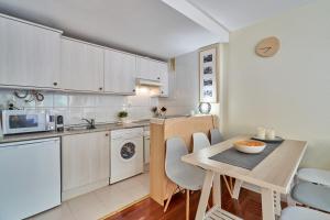 a kitchen with white cabinets and a table with chairs at Magnífico Ático Duplex con vistas a la montaña in Canfranc-Estación