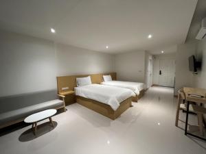 a bedroom with two beds and a bench in it at Super Highway Hotel in Tha Chang