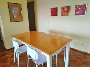 Amplio depto de 2 dormitorios, Zona Plaza Uruguaya في أسونسيون: طاولة خشبية مع كراسي بيضاء ولوحات على الحائط