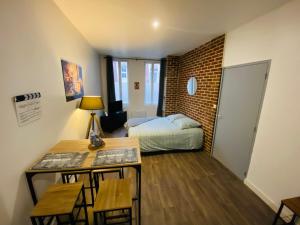 a small room with a bed and a desk with a table sidx sidx at Le Studio 11 Abbeville centre baie de Somme in Abbeville