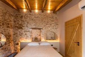 a bedroom with a bed and a brick wall at Casa Coo in Dhafnédhes