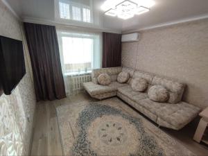 un soggiorno con divano e tappeto di 2-х комнатная квартира в центре на ул.Бородина 107 a Qostanay