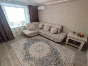un soggiorno con divano e tavolo di 2-х комнатная квартира в центре на ул.Бородина 107 a Qostanay