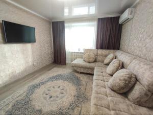 un soggiorno con divano e TV a schermo piatto di 2-х комнатная квартира в центре на ул.Бородина 107 a Qostanay