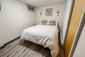 um pequeno quarto com uma cama com lençóis brancos e almofadas em Runaway to Winhall em Stratton Valley