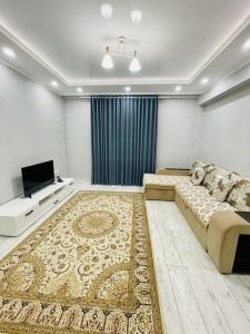 uma sala de estar com um sofá e uma televisão de ecrã plano em # 268 Светлая и уютная квартира em Atyrau
