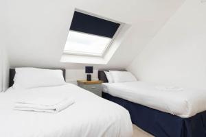 2 camas en una habitación con ventana en Modern newly refurbished house 10 minute walk from Lahinch, en Lahinch