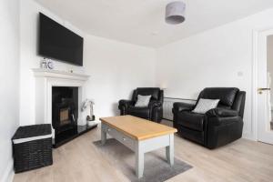 a living room with two leather chairs and a fireplace at Modern newly refurbished house 10 minute walk from Lahinch in Lahinch