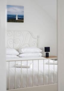 a white bed with a white headboard and a lighthouse at Modern newly refurbished house 10 minute walk from Lahinch in Lahinch