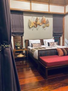 1 dormitorio con 1 cama y un banco con zapatos en la pared en SAK-KA-YA (สัก-กา-ยะ), en Mae Sot