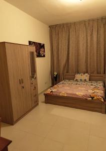 a bedroom with a bed and a wooden cabinet at Private Room In shared apartment in heart of Ajman in Ajman 