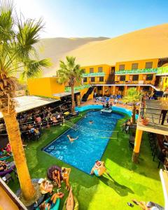 a resort with a swimming pool with people in it at Wild Rover Huacachina in Ica