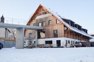 a large wooden building with snow in front of it at Trautesheim Ferienwohnungen in Wangen im Allgäu