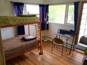 a bedroom with bunk beds and a desk and a table at Base Camp Anchorage Hostel in Anchorage