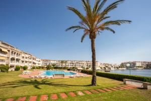 un palmier et une piscine dans un complexe dans l'établissement 1011 Piso Lago San Maurici con piscina y jardín, à Empuriabrava