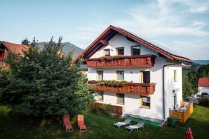 Casa blanca con balcones, mesas y sillas en Ferienwohnungen Schmid, en Lam