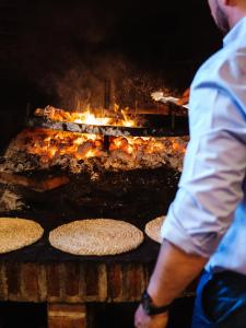 a man is standing in front of a grill with food at Posada Real de Carreteros in Casarejos