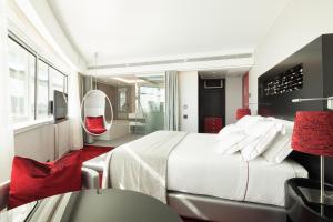 um quarto com uma cama branca e uma cadeira vermelha em MYRIAD by SANA Hotels em Lisboa