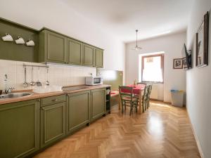 eine Küche mit grünen Schränken und einem Tisch mit Stühlen in der Unterkunft Berghi Hotel and Apartments in Kranjska Gora