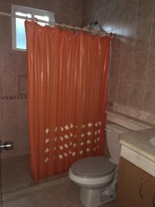 a bathroom with a toilet and an orange shower curtain at CASA PALMA REAL PLAYACAR in Playa del Carmen