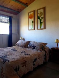 um quarto com uma cama e duas fotografias na parede em Posada del Corumbá em La Paloma