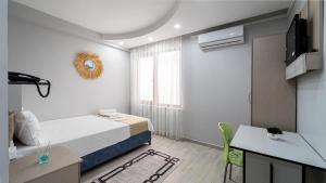 een kleine kamer met een bed, een bureau en een televisie bij KUMBAĞ ŞEHRİ SARAY APART OTEL in Tekirdag