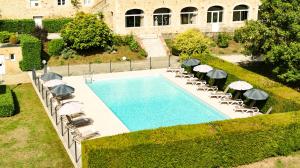 - une vue sur la piscine entourée de chaises longues et de parasols dans l'établissement Château de Fontanges, à Onet le Château