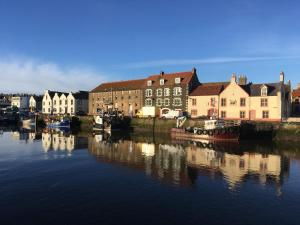 a city with buildings and boats in the water at Harbourside Apartment in Eyemouth