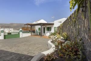 a house with a stone wall and some flowers at Villa Laura Guatiza in Guatiza