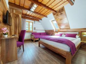 1 dormitorio con 1 cama grande y sillas moradas en PLITVICE ETNO HOUSE II, en Jezerce