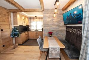 a kitchen with a table and a tv on a wall at "Apartament Przy Termie" Bukowina- Jacuzzi na wyłączność - - niezależne wejście in Bukowina Tatrzańska