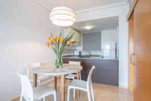a dining room with a table with a vase of flowers at Pierre & Vacances Apartamentos Benidorm Horizon in Benidorm