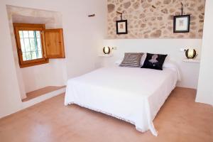 a bedroom with a white bed with a picture on it at Son Vell. Mallorca. Casa amb piscina ecològica. in Manacor