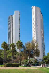 zwei hohe Gebäude mit Palmen in einem Park in der Unterkunft Pierre & Vacances Apartamentos Benidorm Horizon in Benidorm