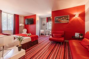 - une chambre avec des murs rouges, un lit et un canapé dans l'établissement Hostellerie du Passeur - Hôtel & Restaurant - Climatisation et Piscine chauffée, à Les Eyzies-de-Tayac