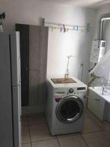 uma máquina de lavar roupa numa cozinha com um frigorífico em APT A 10 MIN DA CIDADE DE PENEDO em Resende
