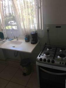 uma cozinha com um fogão, um lavatório e uma janela em APT A 10 MIN DA CIDADE DE PENEDO em Resende